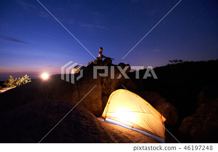 Camping at night on rock formation. Tourist tent and woman doing yoga on mountain top 46197248