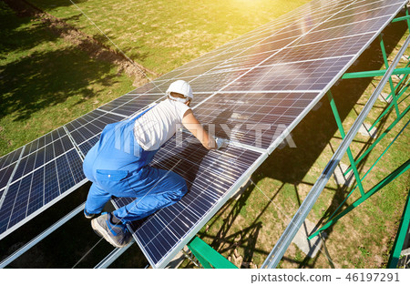 Professional worker installing solar panels on the green metal construction 46197291