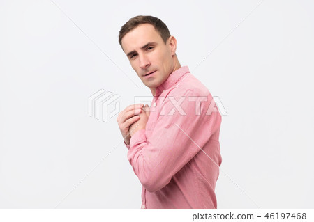 A young greedy man in pink shirt hides something 46197468