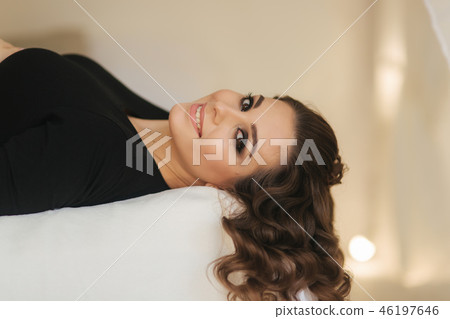Beautiful pregnant woman lies on the bed in her room. Young lady with long hair put her hands on 46197646