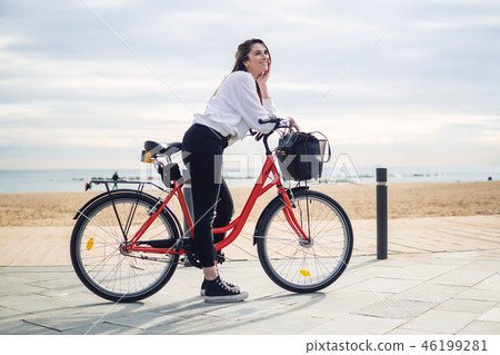 Woman riding bicycle along beach sand at summer time Woman riding bicycle along beach sand at summer time 46199281