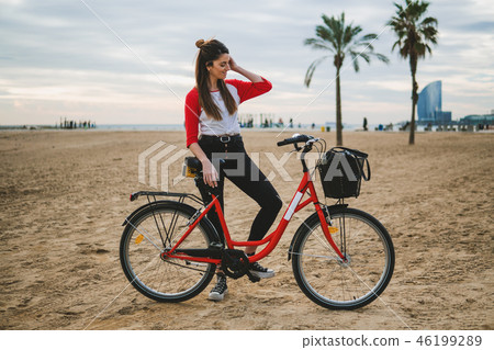 Woman riding bicycle along beach sand at summer time Woman riding bicycle along beach sand at summer time 46199289