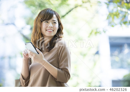 Woman looking at smartphone outdoors 46202326