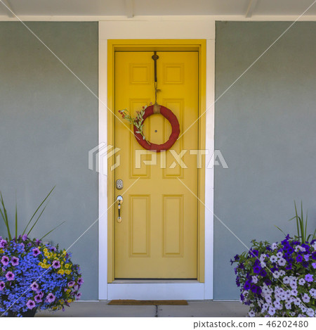 Front door with wreath and colorful potted flowers 46202480