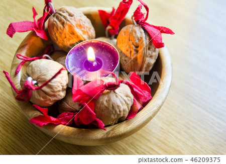 purple candle with decorated wallnuts in a bowl. purple candle with decorated wallnuts in a bowl. 46209375