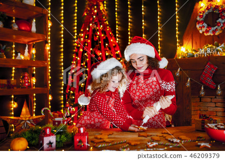 Merry Christmas and Happy Holidays. Cheerful cute curly little girl and her older sister in santas Merry Christmas and Happy Holidays. Cheerful cute curly little girl and her older sister in santas 46209379