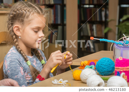 The girl knits embroidery in the school library 46213180