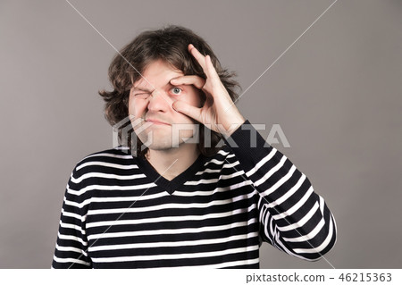 A man widen his eye with thumb and forefinger. Tired guy open his eye widely with fingers, having A man widen his eye with thumb and forefinger. Tired guy open his eye widely with fingers, having 46215363