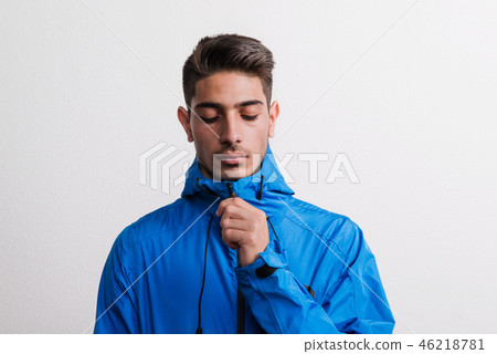 Portrait of a young serious hispanic man with blue anorak in a studio. 46218781