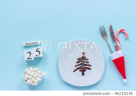 Xmas composition Calendar December 25th. Sweet chocolate Christmas tree on plate, cutlery in santa Xmas composition Calendar December 25th. Sweet chocolate Christmas tree on plate, cutlery in santa 46219136