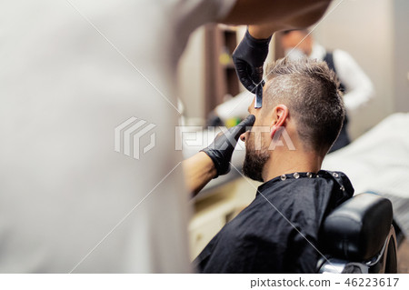 A man client visiting haidresser and hairstylist in barber shop. A man client visiting haidresser and hairstylist in barber shop. 46223617