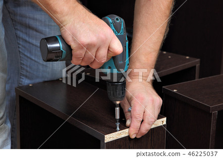 Hands carpenter with screwdriver, tighten screw  46225037