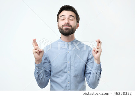 Hispanic man standing with crossed fingers Hispanic man standing with crossed fingers 46238352