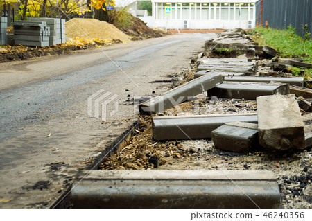 Broken freshly dug up old curbstones with pieces of an asphalt and earth lying on the road in Moscow 46240356