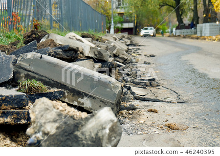 Broken freshly dug up old curbstones with pieces of an asphalt and earth lying on the road in Moscow Broken freshly dug up old curbstones with pieces of an asphalt and earth lying on the road in Moscow 46240395