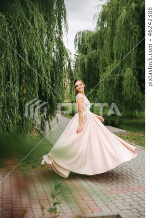 Fashionable girl spin around in park. Evening dress Fashionable girl spin around in park. Evening dress 46242388