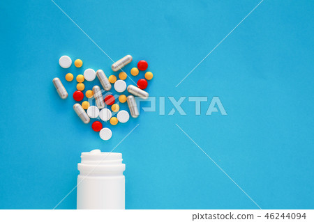 Pills heart out of pill bottle on blue background. Pills heart out of pill bottle on blue background. 46244094