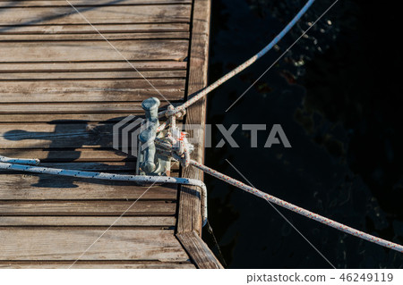 Yachting detail, rope and mooring double cross bollard on bridge in port of sailing. Wooden pier 46249119