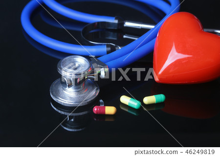 stethoscope, Red heart and assorted pils on black mirror background. Selective focus. stethoscope, Red heart and assorted pils on black mirror background. Selective focus. 46249819