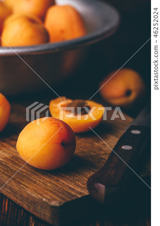 Mellow apricots with knife over cutting board 46252024