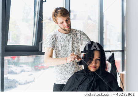 Smiling woman getting haircut by handsome hairdresser Smiling woman getting haircut by handsome hairdresser 46252901
