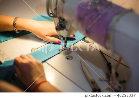 Girl seamstress in the light of a desk lamp stitch 46253337