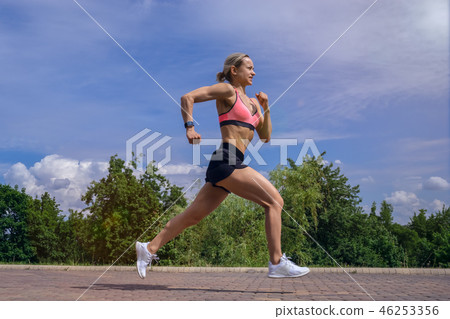Fit woman running fast for sport on sunny day Fit woman running fast for sport on sunny day 46253356