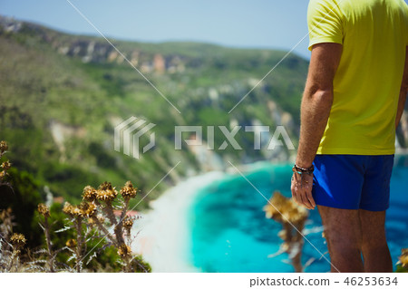 Male tourist wearing shorts on Petani beach Kefalonia enjoying picturesque panorama of emerald azure 46253634