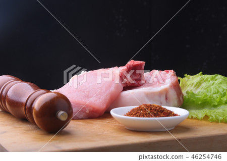 Raw steak on rustic cutting board with salt, pepper and grinder for spices. Black Background for 46254746