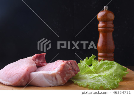 Raw steak on rustic cutting board with salt, pepper and grinder for spices. Black Background for 46254751