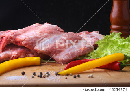 Raw Ribs on a rustic cutting board with salt, pepper and grinder for spices . Black Background for Raw Ribs on a rustic cutting board with salt, pepper and grinder for spices . Black Background for 46254774