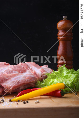 Raw Ribs on a rustic cutting board with salt, pepper and grinder for spices . Black Background for 46254776