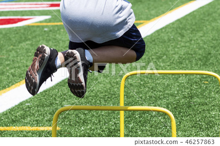Young boy jumping over yellow mini hurdles Young boy jumping over yellow mini hurdles 46257863