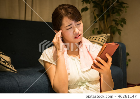 看智能手機的疲乏的眼睛年輕日本婦女在屋子裡 46261147
