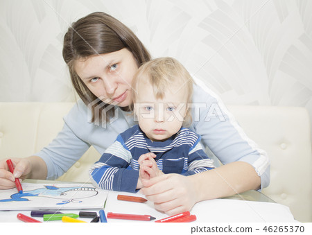 Mother and son are drawing together with pencils at table 46265370