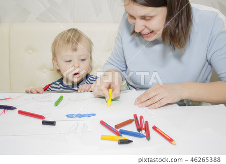 Mother and son are drawing together with pencils at table Mother and son are drawing together with pencils at table 46265388