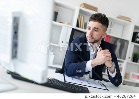 A young man sitting in the office at a computer Desk and working with documents. 46267264
