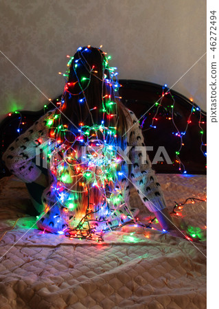 The girl is wrapped up with Christmas garlands. The girl is wrapped up with Christmas garlands. 46272494