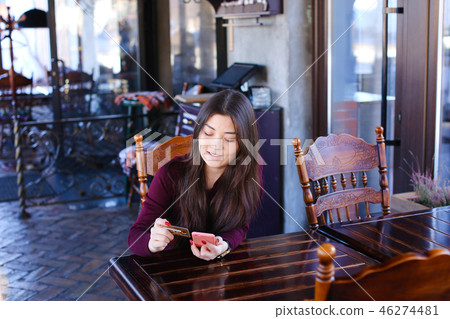 Teacher checking tests in cafe using smartphone 46274481