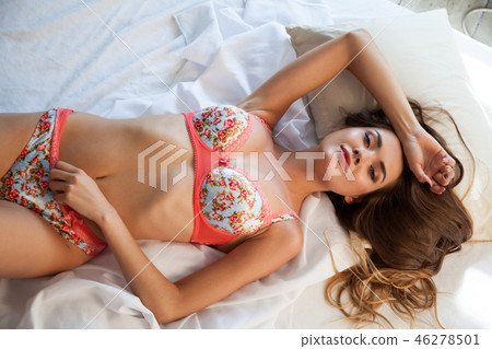 PORTRAIT OF BEAUTIFUL WOMAN IN UNDERWEAR WITH FLOWERS ON A WHITE BACKGROUND PORTRAIT OF BEAUTIFUL WOMAN IN UNDERWEAR WITH FLOWERS ON A WHITE BACKGROUND 46278501