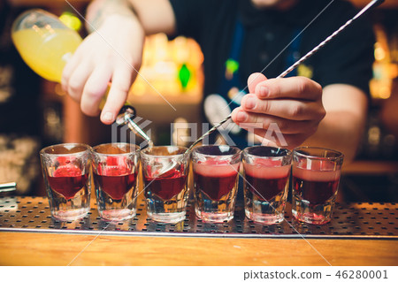 Bartender is pouring tequila into glass against the background of the bar. Bartender is pouring tequila into glass against the background of the bar. 46280001
