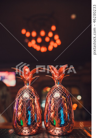 Two cocktails in the pineapple form cups on the bar counter. Two cocktails in the pineapple form cups on the bar counter. 46280233