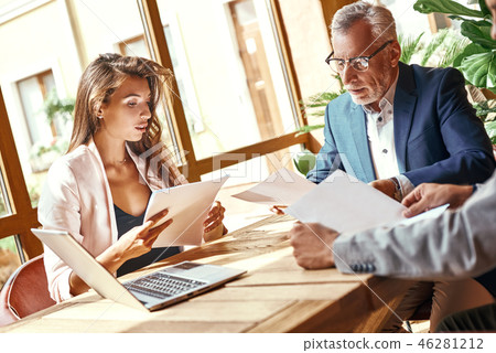 Business lunch. Three people in the restaurant sitting at table making deal senior man shaking hands Business lunch. Three people in the restaurant sitting at table making deal senior man shaking hands 46281212