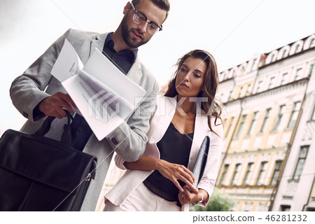 Preparing for meeting. Two young business people walking outside on the city street reading through 46281232