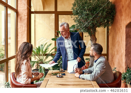 Business lunch. Three people in the restaurant sitting at table boss giving documents to employees 46281631