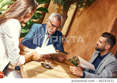 Business lunch. Three people in the restaurant sitting at table discussing project joyful close-up Business lunch. Three people in the restaurant sitting at table discussing project joyful close-up 46281632