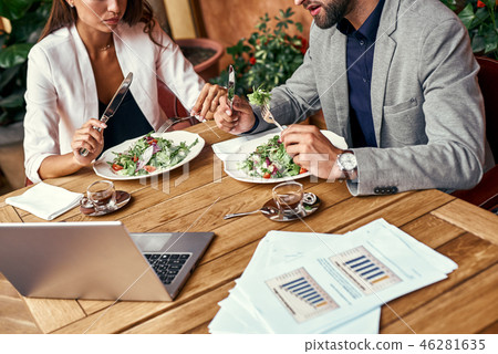 Business lunch. Man and woman sitting at table at restaurant eating healthy fresh salad discussing Business lunch. Man and woman sitting at table at restaurant eating healthy fresh salad discussing 46281635