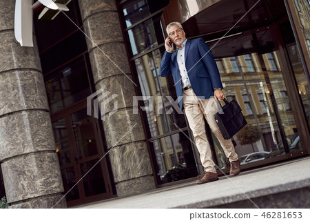 Successful businessman. Serious senior man in casual suit talking on the phone while walking Successful businessman. Serious senior man in casual suit talking on the phone while walking 46281653
