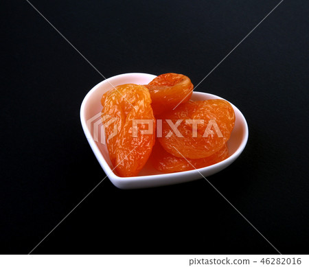 Delicious dried organic apricots on bowl isolated on black background. Delicious dried organic apricots on bowl isolated on black background. 46282016