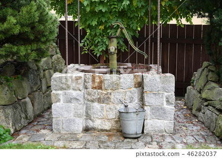Stone well with water pump in the garden Stone well with water pump in the garden 46282037